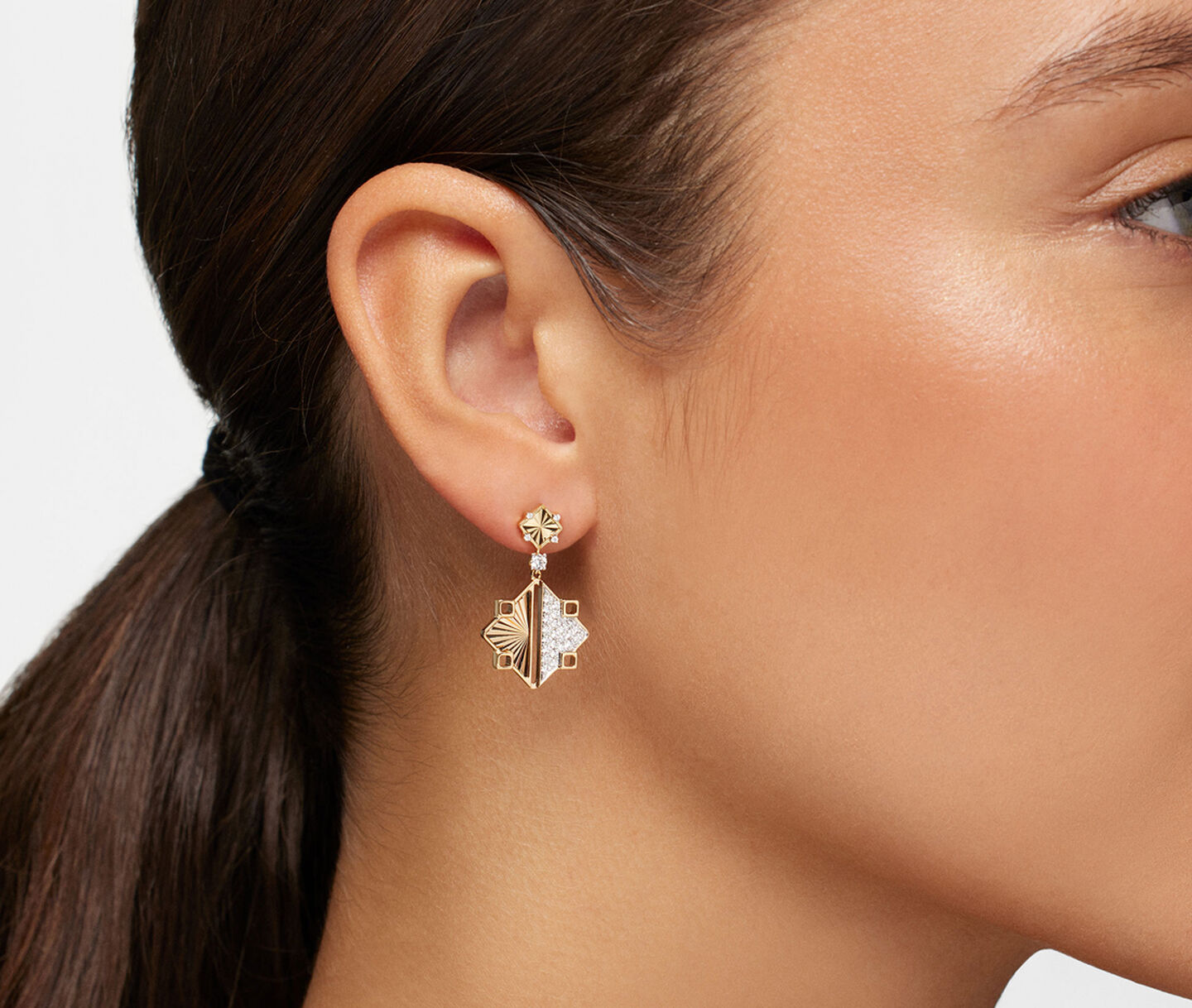A woman wearing Birks Muse yellow gold and diamond drop earrings.